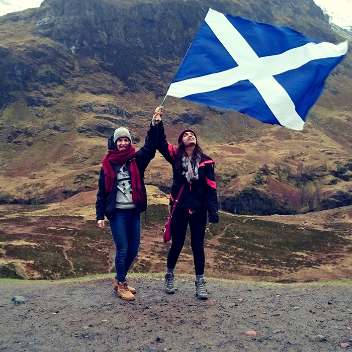 Two people holding up a Scotish flag in the highlands