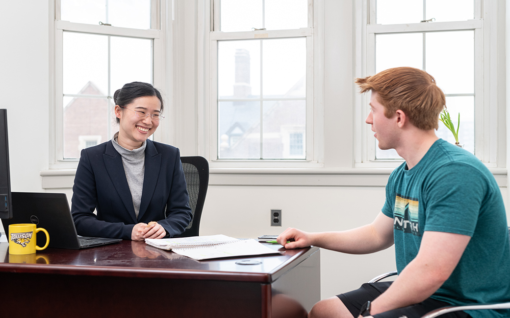 Faculty member assists student with work at a desk