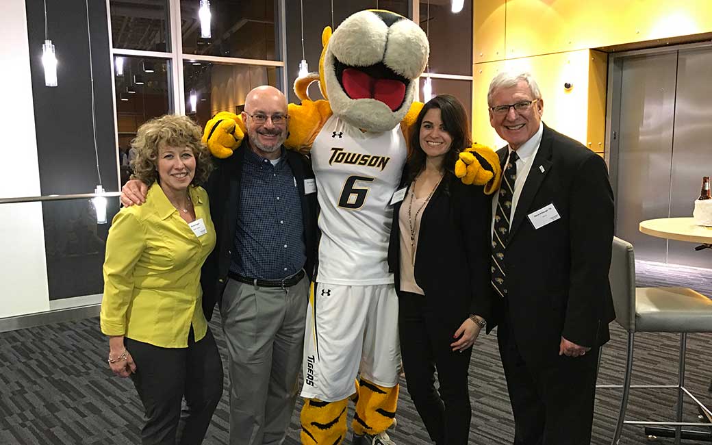 Member of the CBE Advisory Board pose with Doc at a men's basketball game