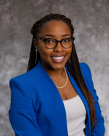 Professor Iesha Pankey smiles at the camera in a bright blue blazer and black glasses