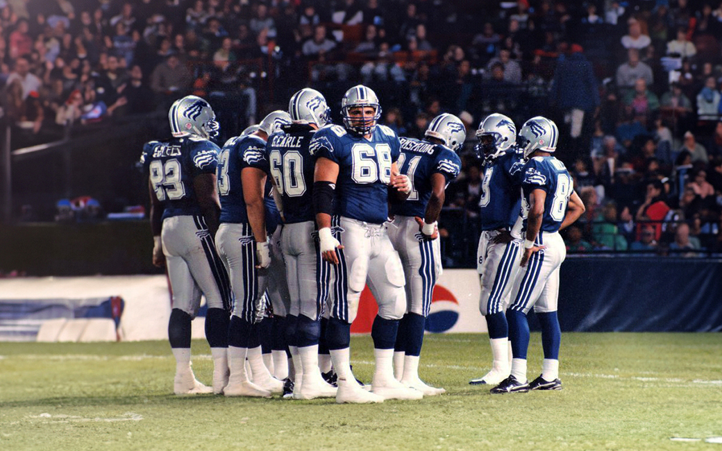 Offensive lineman Shar Pourdanesh stares down the camera as his teammates form a huddle in front of a crowd of fans