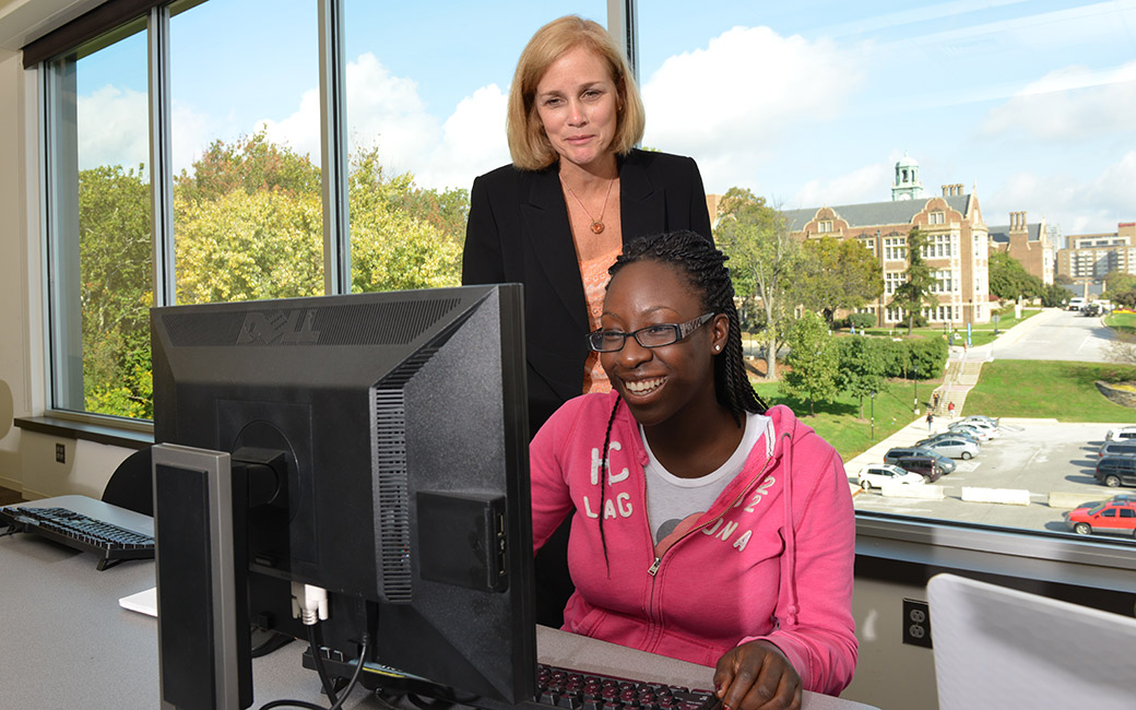 Professor and student interacting in front of computer.