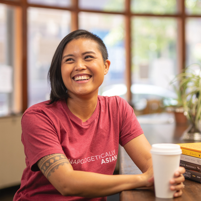 Cori Dioquino sitting with a cup of coffee