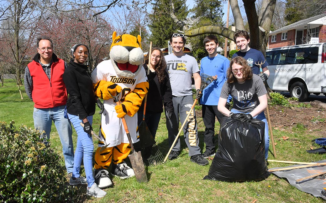 Students, Doc, and a member of the local community work together in a yard.