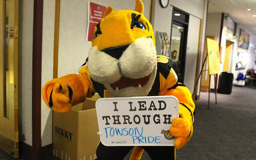 Doc holding a sign that reads "I lead through Towson Pride"
