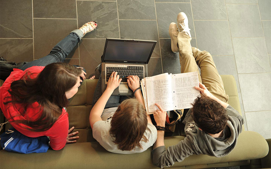 Students working together on a laptop in a lounge